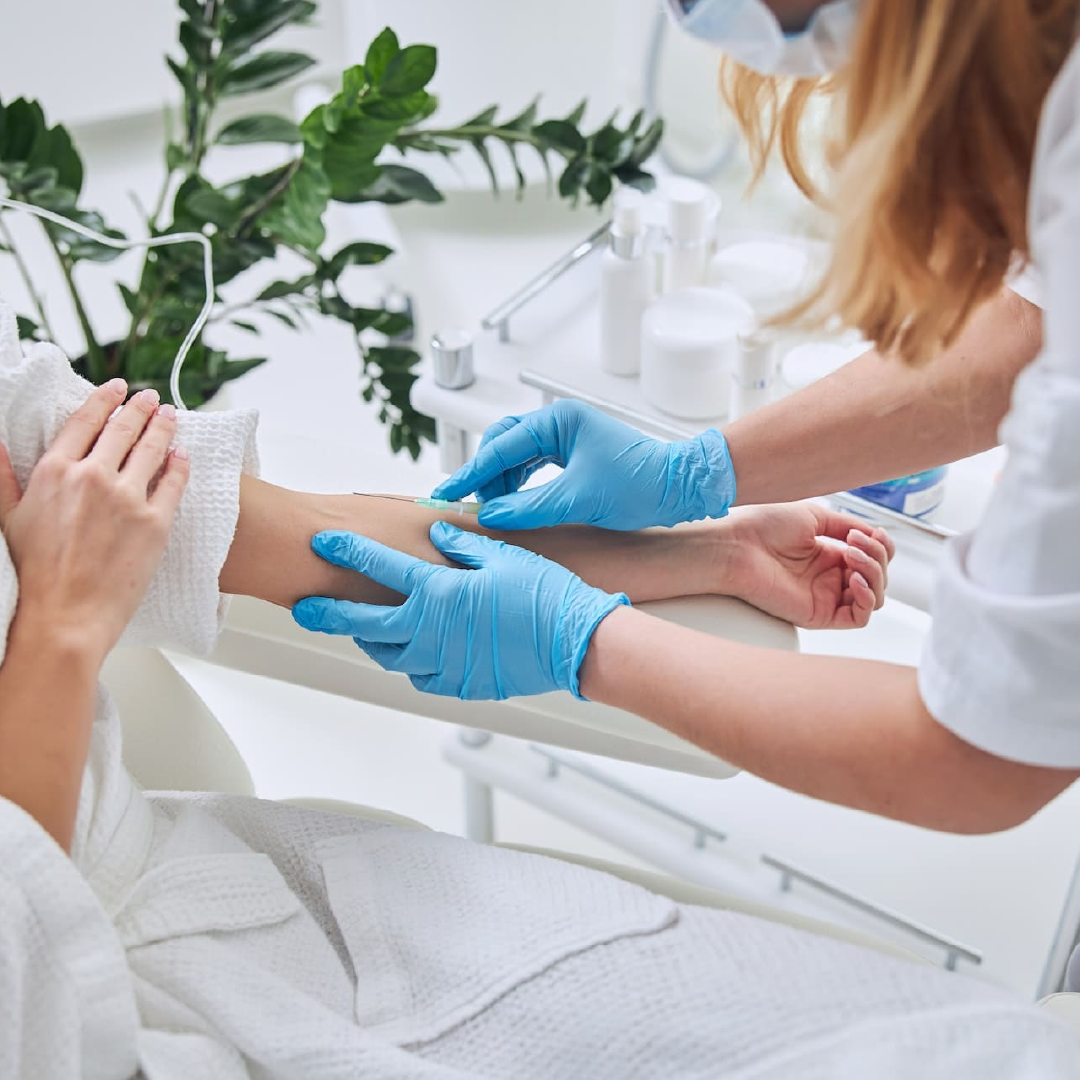 Gloved hands preparing an arm for IV therapy as part of a wellness and anti-aging plan.